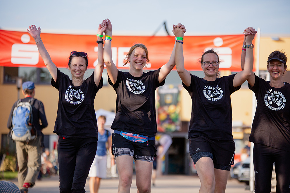 Frauengruppe die mit erhobenen Armen durch das Ziel marschiert