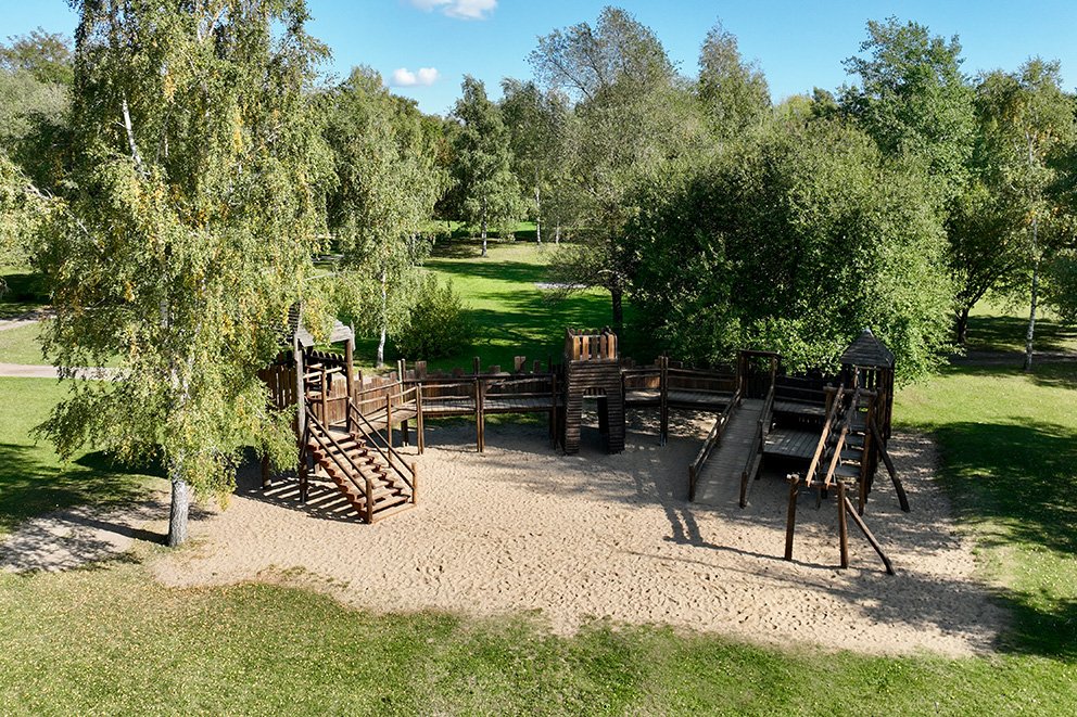 Drohnenaufnahme die eine Holz Burg auf dem Abenteuerspielplatz zeigt